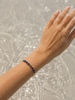 Hand with a blue sodalite bracelet against a water background