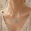 Necklace with a dragonfly pendant worn by a person in a white lace top.