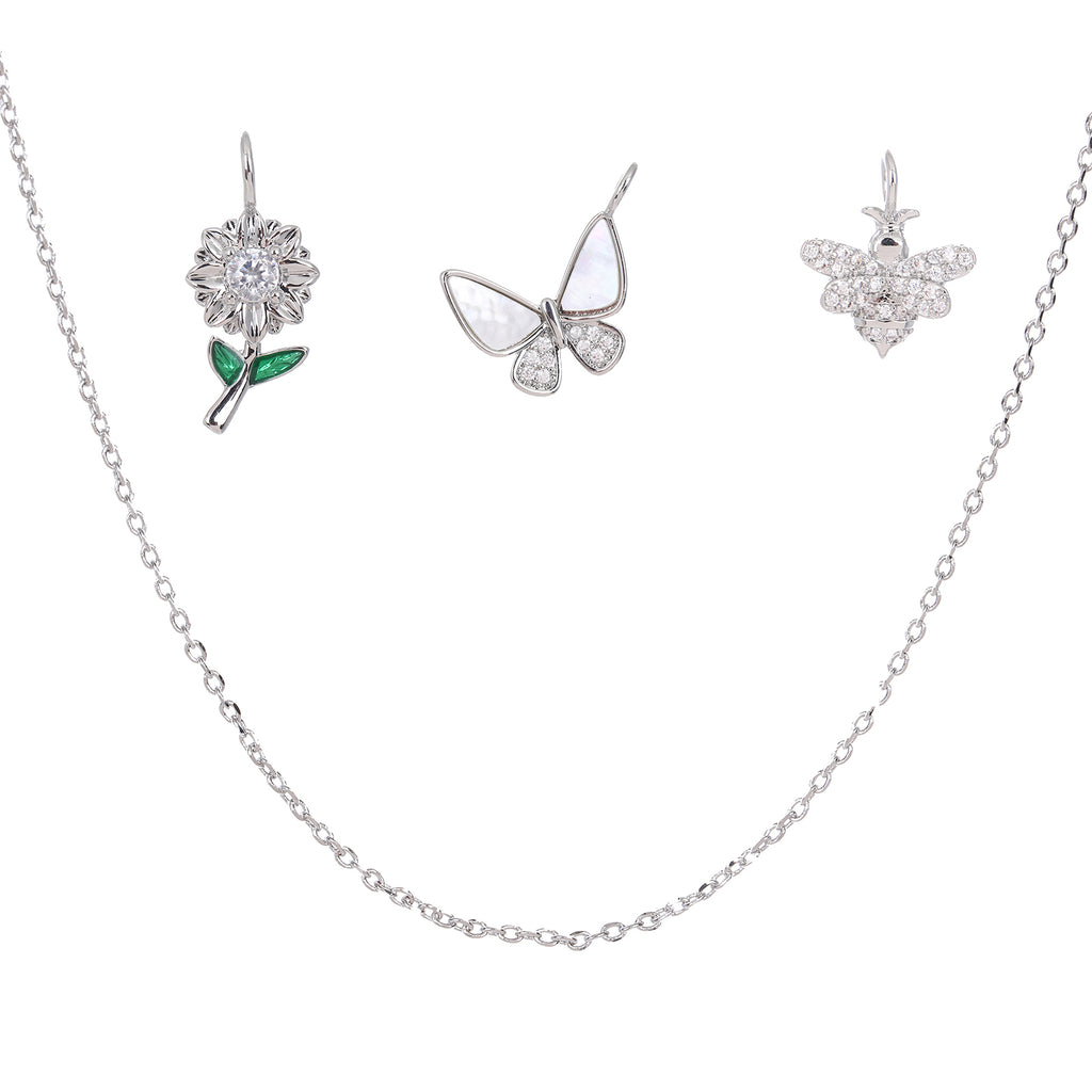 Silver jewelry set with necklace floral, butterfly and bee charms on a white background