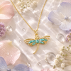 Gold necklace with a dragonfly pendant on a soft floral background