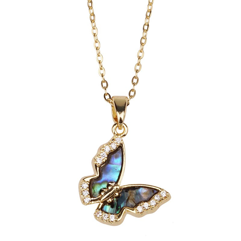 Butterfly-shaped pendant with abalone shell and crystals on a gold chain against a white background