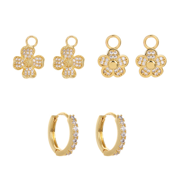 Set of gold huggie hoop earrings including  flower, and hoop designs on a white background