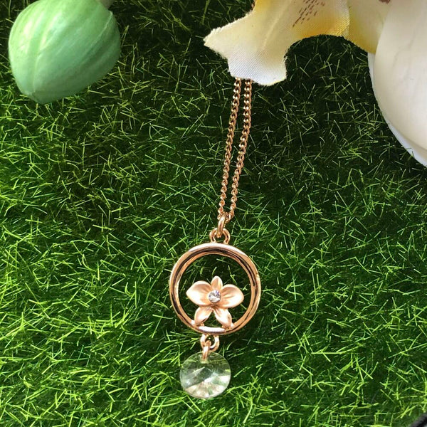 necklace pendant in rose gold plating with orchid flower and drop crystal from forest jewelry on grass