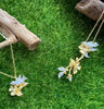 canary bird pendant short and long flatlay on grass with wood from forest jewelry singapore